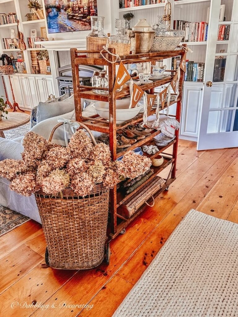 French basket with fall hydrangeas, vintage cobbler rack in open floor plan living room as room divider.