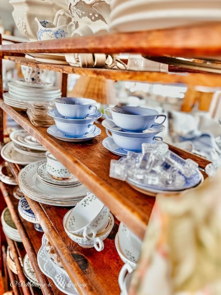 Vintage blue bowls and other vintage collections on a wooden cobbler rack.