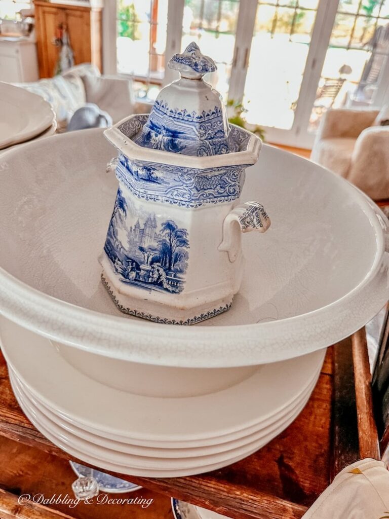 Vintage blue and white jar in ironstone bowl on top of white dishes.