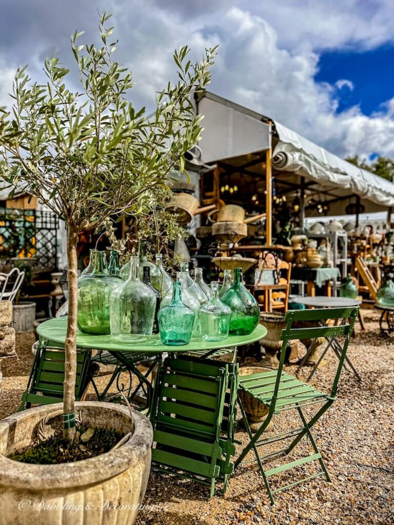 Antique green bottles and garden table at antique flea market in Paris.