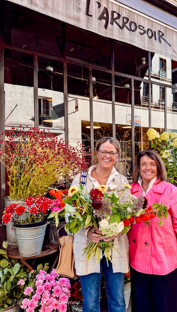 Two women holding a French flower bouquet outside a Parisian Flower shop.