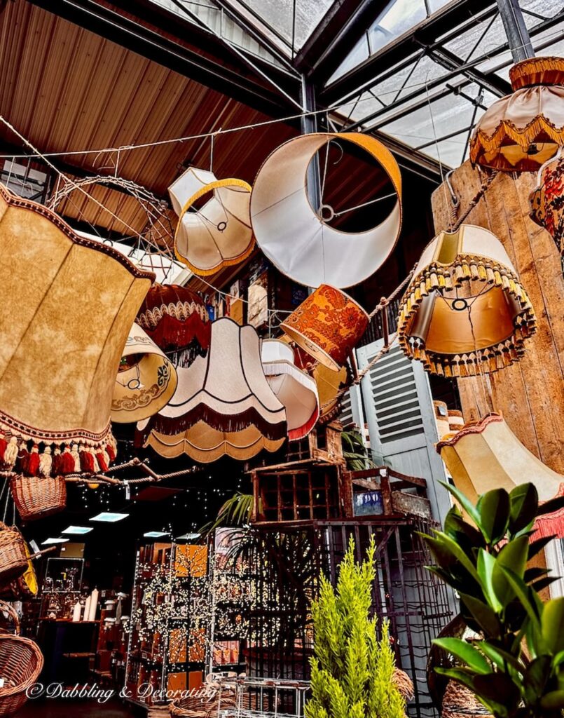 Antique lampshades hanging upside down from ceiling in private warehouse in Paris.