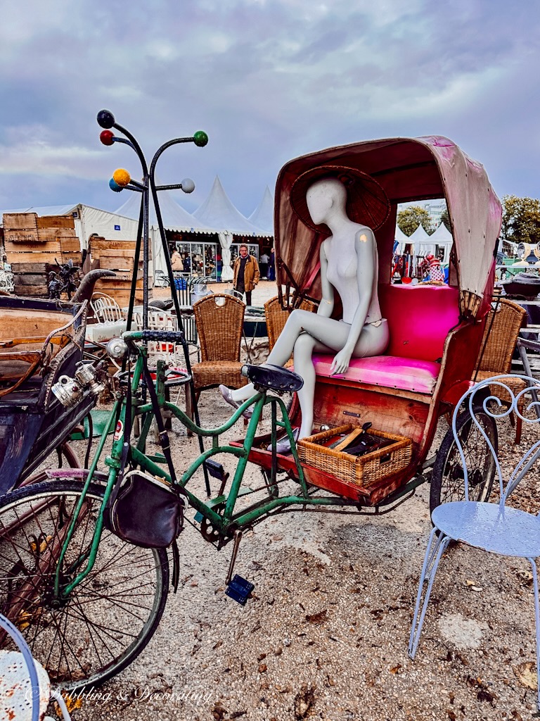 Antique carriage with mannequin at outdoor Paris flea market in the rain.