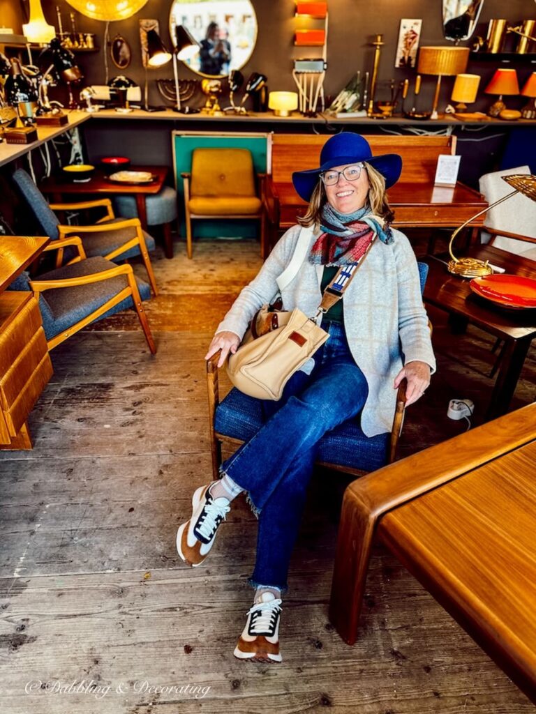 Woman sitting in mid century modern vendors antique booth in Paris.