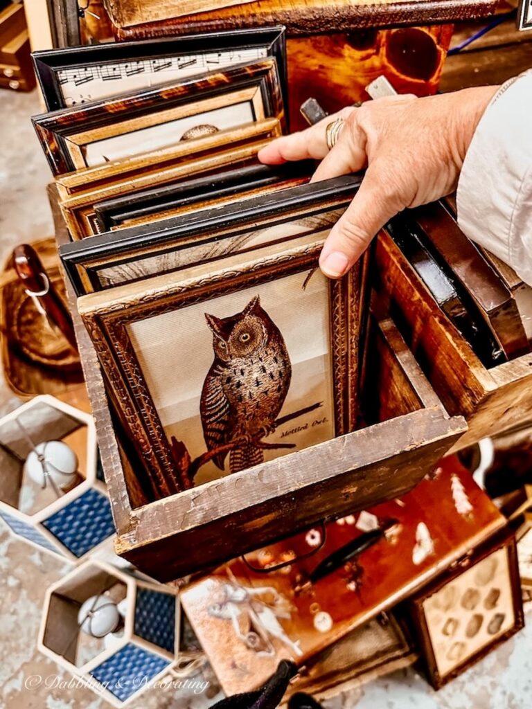 Box full of vintage framed owl prints at vintage market.