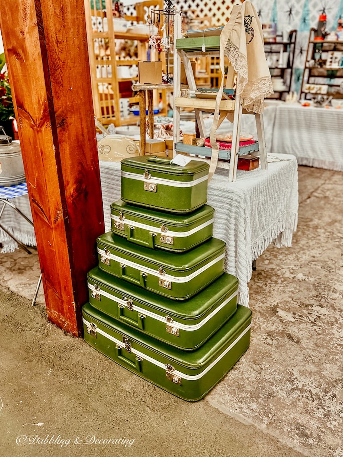 5 retro green vintage suitcases stacked large to smallest at vintage market Vermont fall foliage season.