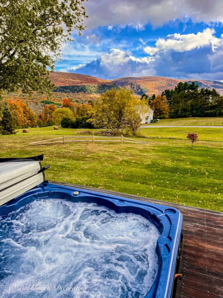 Open blue hot tub in the mountains of Vermont surrounded by peak fall foliage.