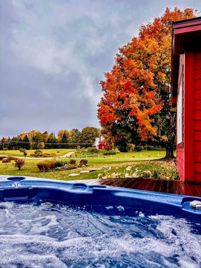 Vermont fall foliage maple tree next to hot tub at a red home.