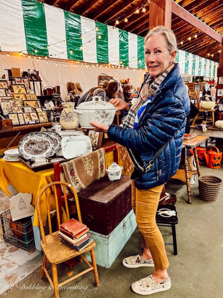 Woman holding a brown and white transferware soup tureen at vintage market.