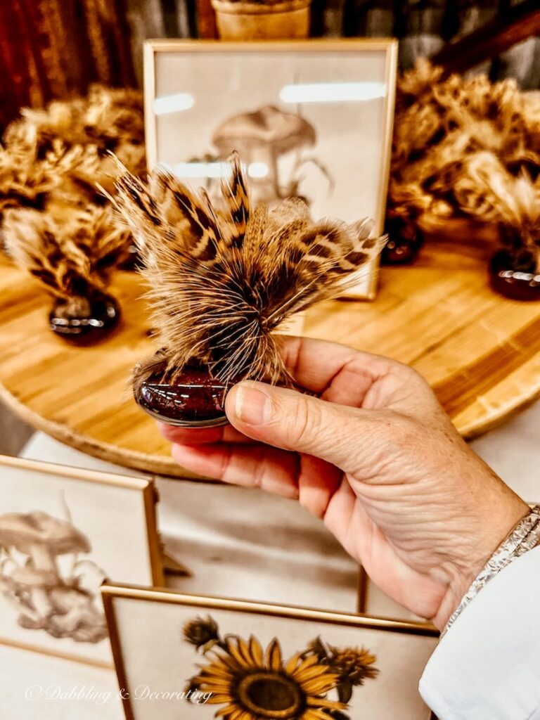 Small door knob with feathers in hand at vintage market.