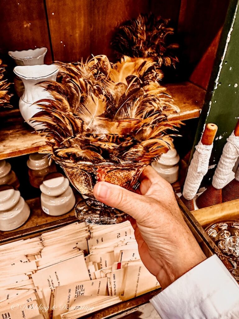 Feathers in silver bowl in hand at vintage market.