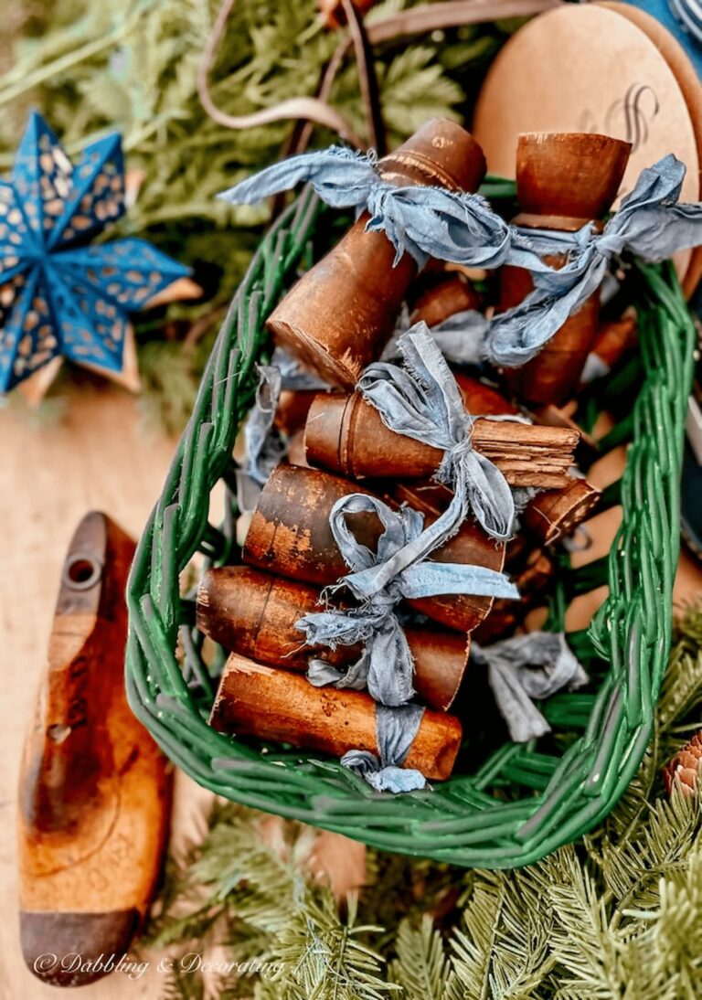 Green basket filled with decorative wood spindles with blue bows for Christmas.