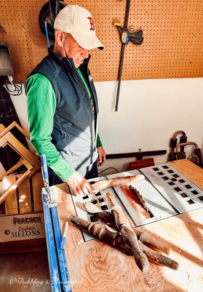 Man in green shirt getting ready to cut decorative wooden spindles at table saw in garage.