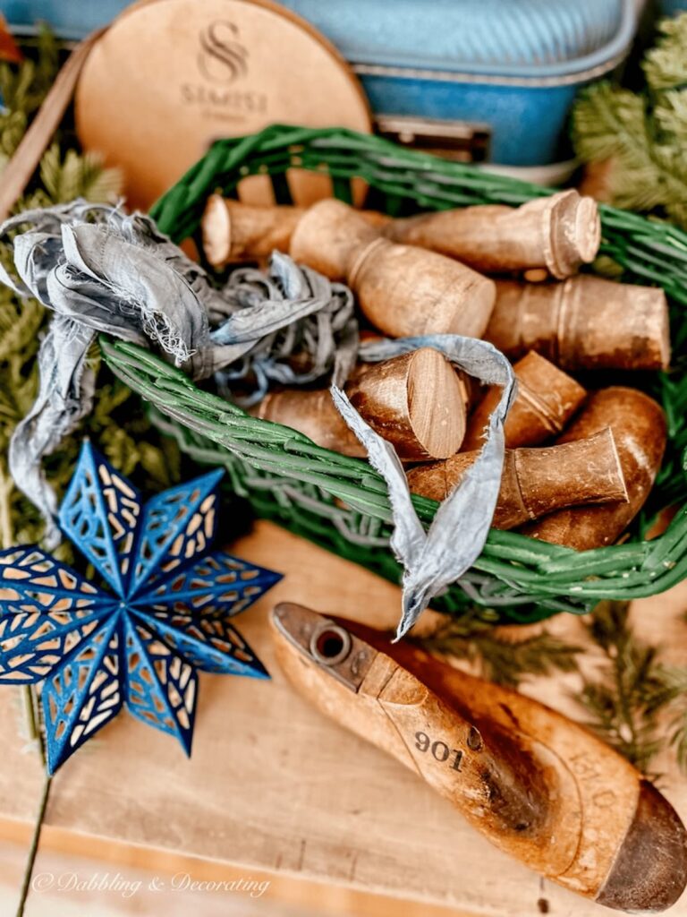 Green basket with decorative wood spindles, blue ribbon, and blue star snowflake on Christmas craft table.