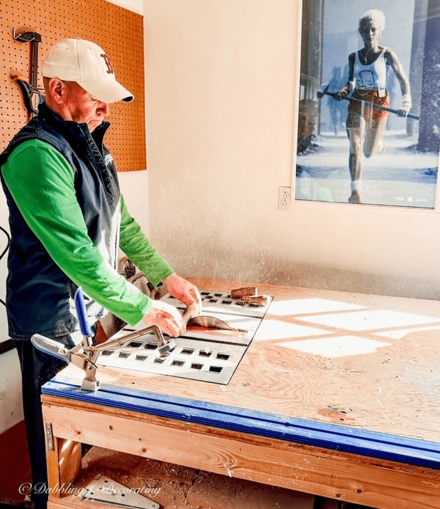 Man in  green shirt at table saw sawing decorative wooden spindles at workbench.