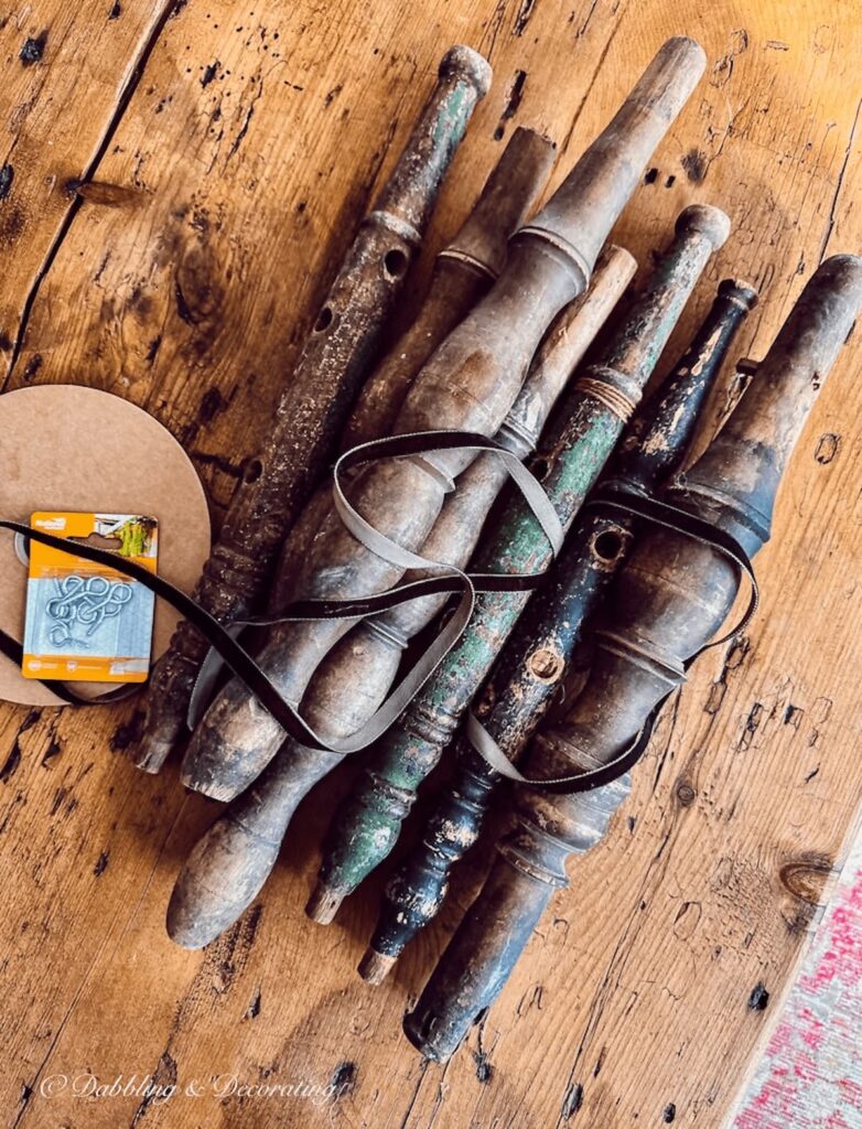 Several decorative wood spools on table with ribbon and screw eyes.