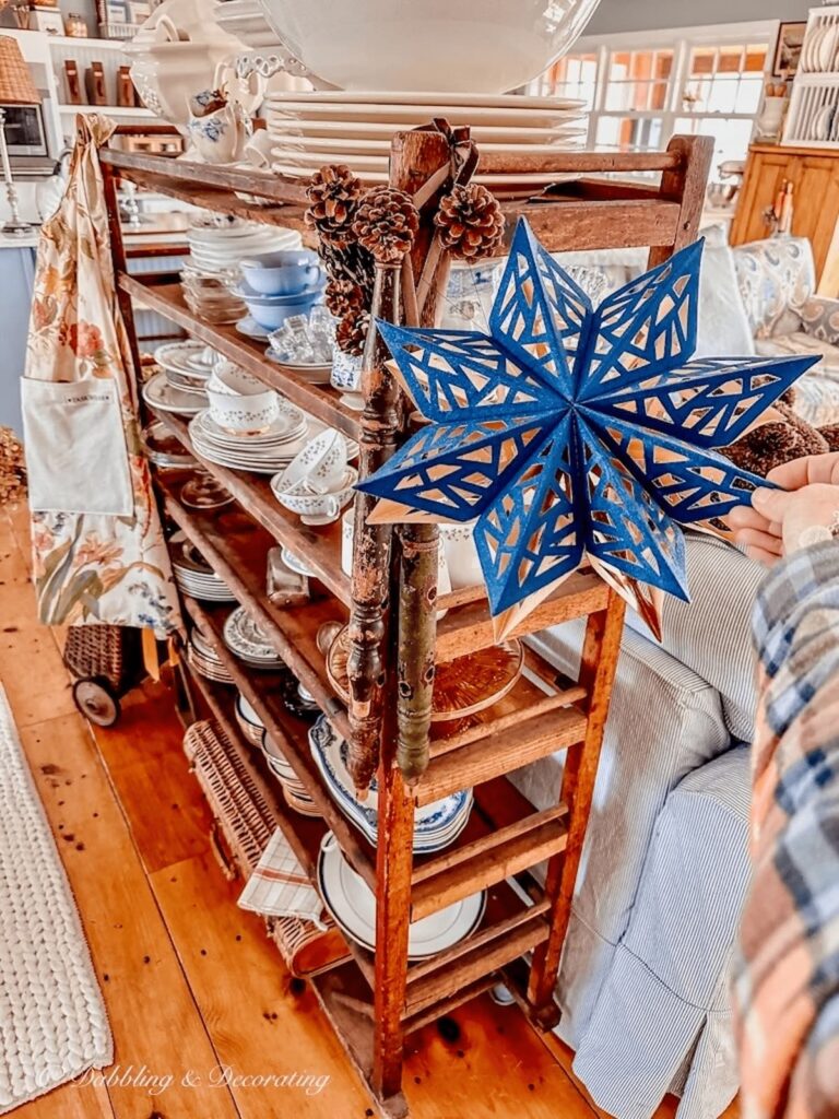 Navy blue star snowflake hanging on vintage cobbler rack with decorative wood spindles.