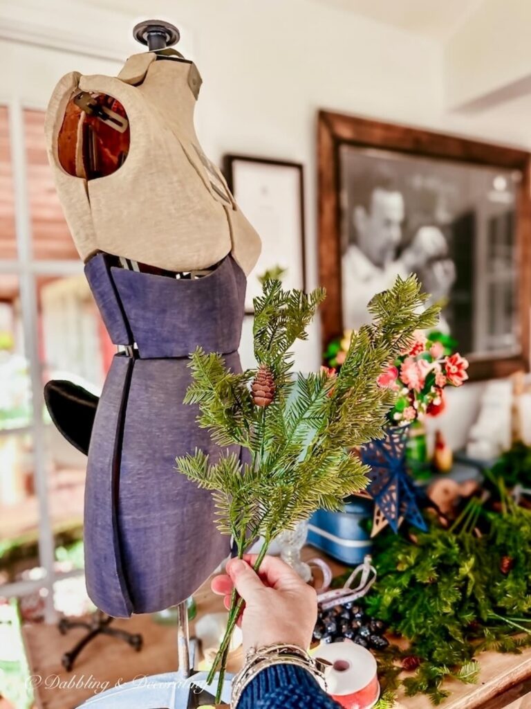 Vintage bust form with evergreen branch in hand in craft room space.