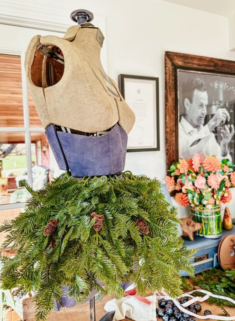 Vintage blue and gray bust form on table with faux evergreens around the waist for Christmas decor.