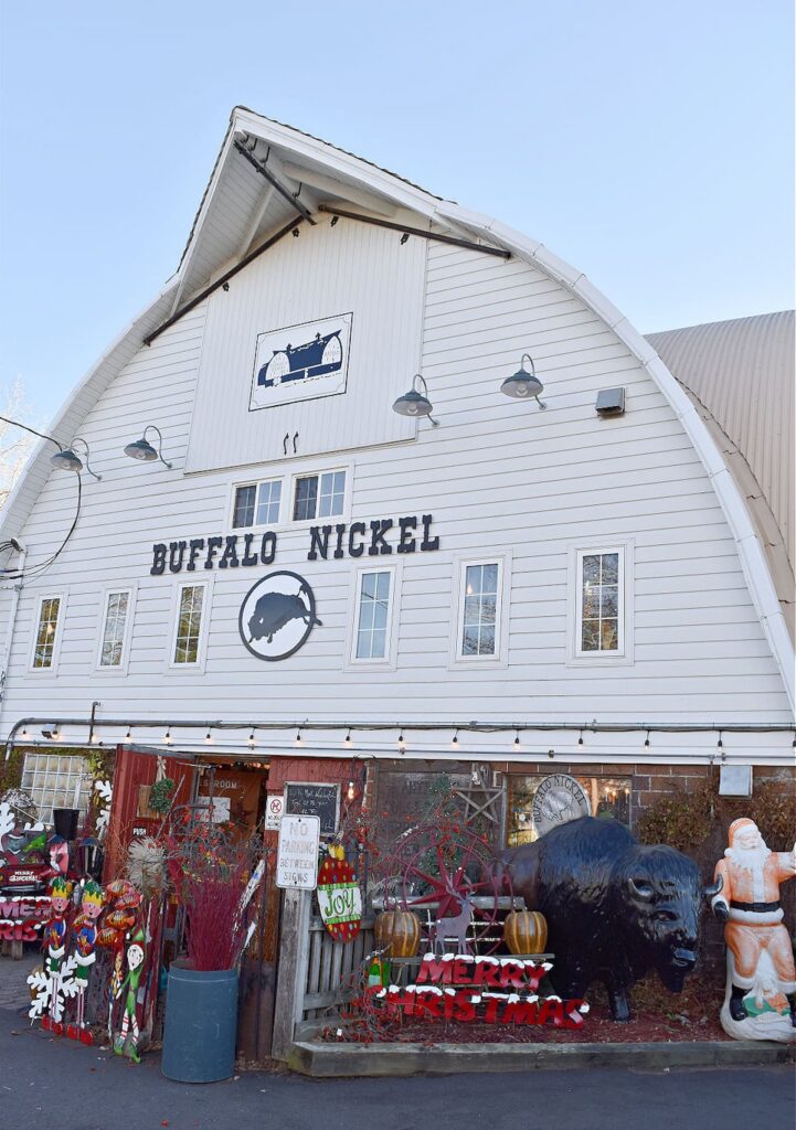 Large white antique barn with Buffalo Nickel written on the outside decorated for Christmas.