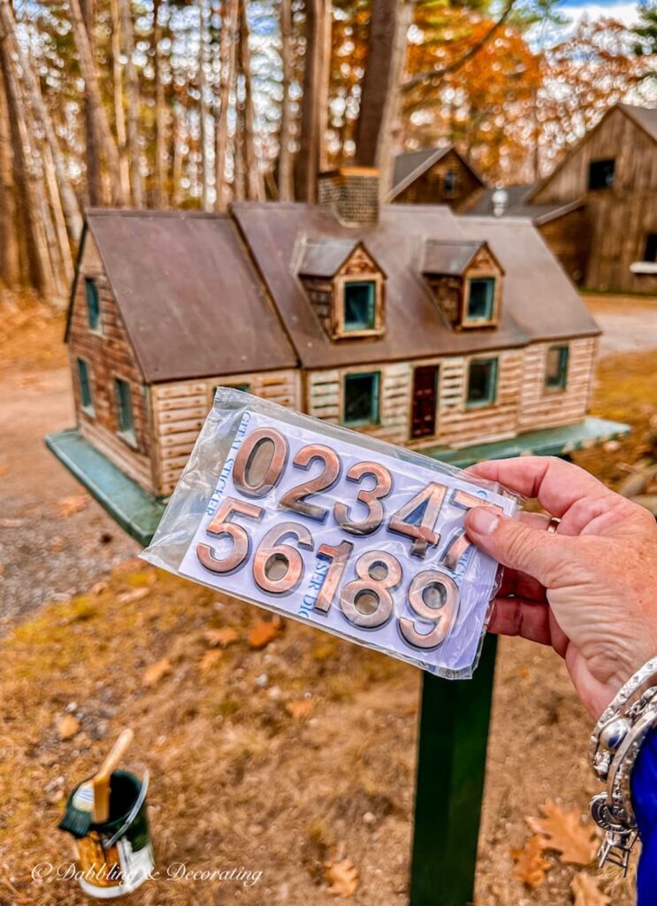 Bronze 3D house numbers in hand in front of house mailbox.