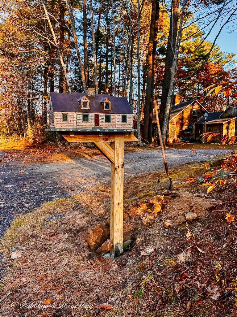 Unique mailbox house on mailbox post in the ground while cement dries.