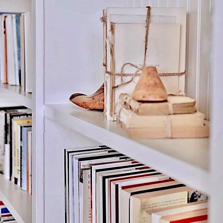 Vintage shoe molds with vintage books on white built-in shelving.