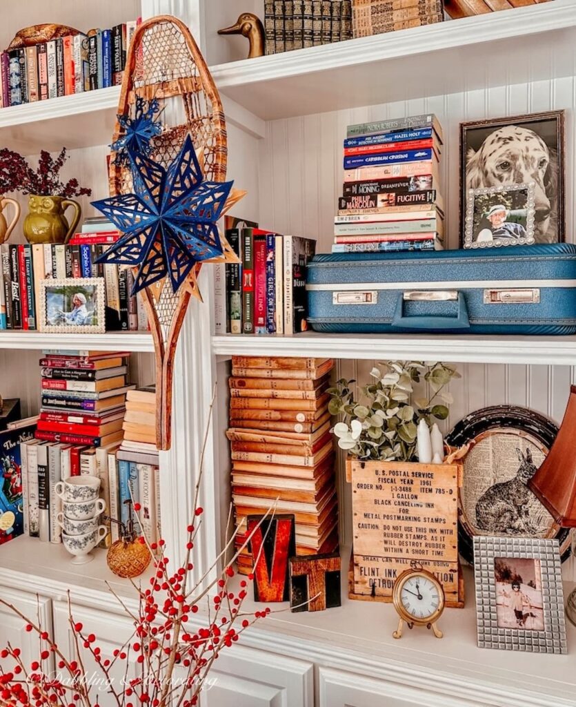 Vintage wooden snowshoe with blue paper star snowflakes hanging on fireside built-ins for a vintage Christmas.