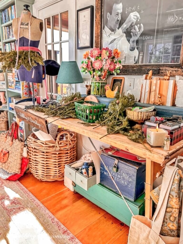 Vintage wallpaper table in craft room space with eclectic holiday decor scattered.