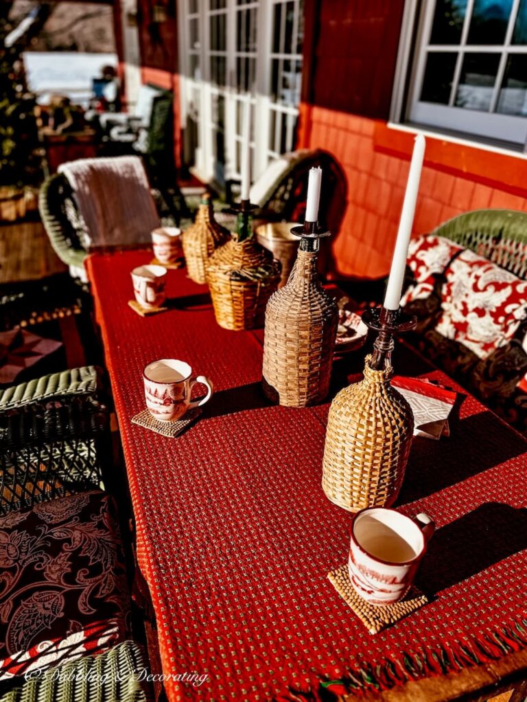 Vintage Demijohn bottles lined up with candles on red set table on Après ski theme porch.