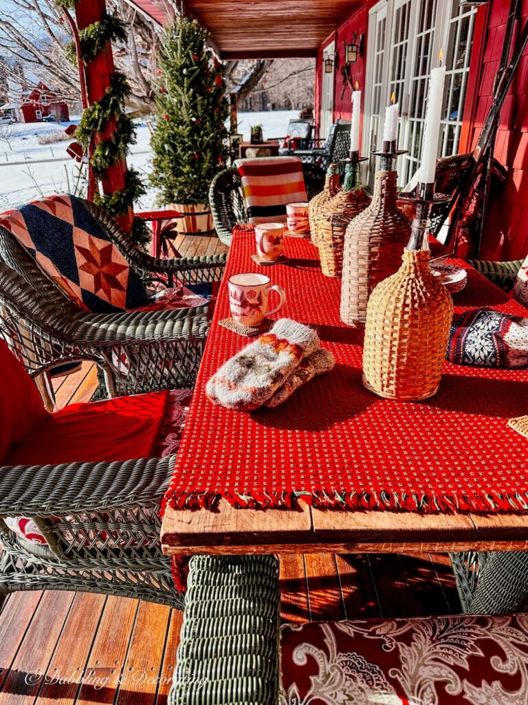 Red winter styled porch table with quilts on chairs on an Après Ski Theme  porch.