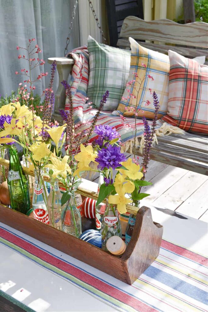 Thrifted decor tool caddy with spring flowers on outdoor porch table.