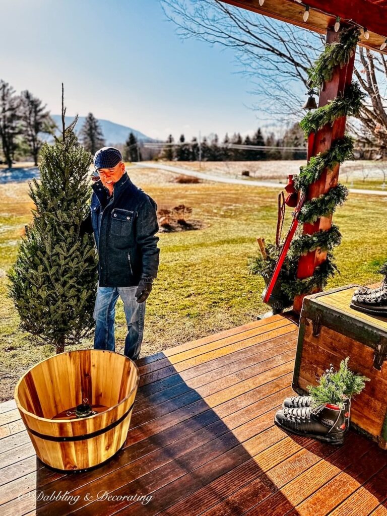 Man with bare Christmas tree and whiskey barrel for Christmas decorating.