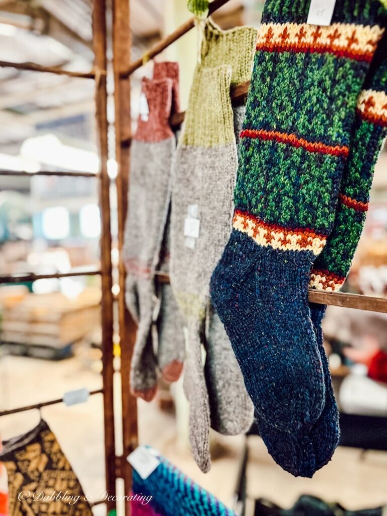 Hand knit stockings in blue and green and yellow hanging at a Farmer's Market.