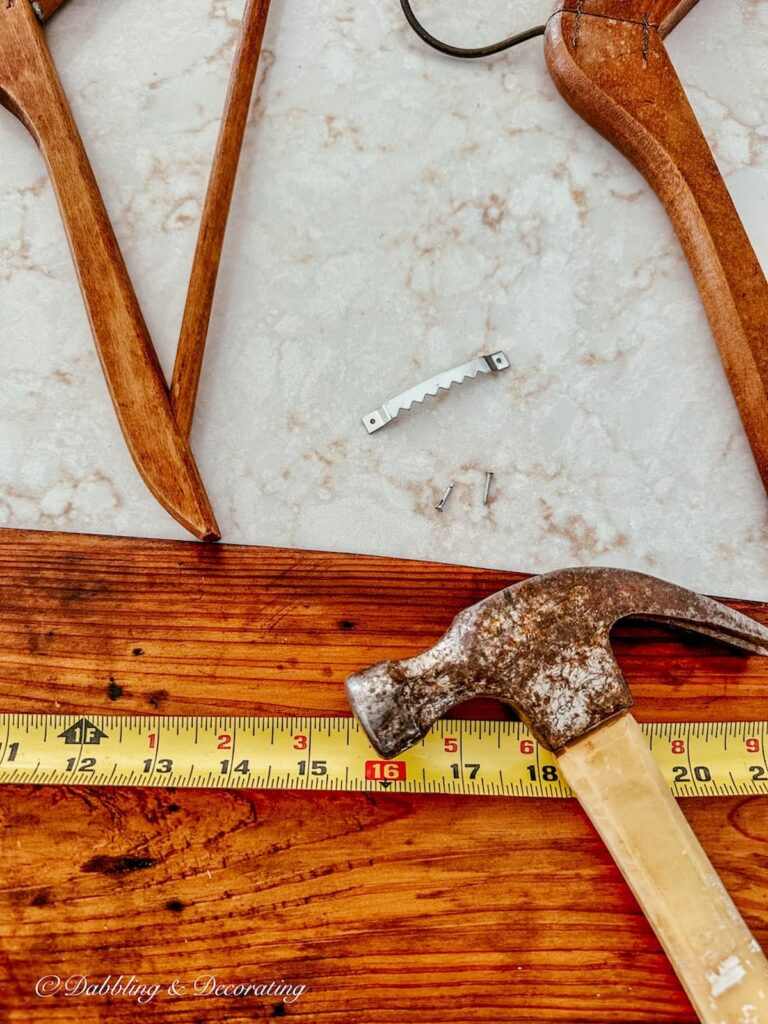 Hammer, tape measure, board and saw booth screw with two screws on counter.