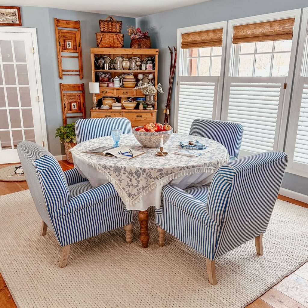 Blue and white dining room styled with vintage decor and three windows with bamboo shades.