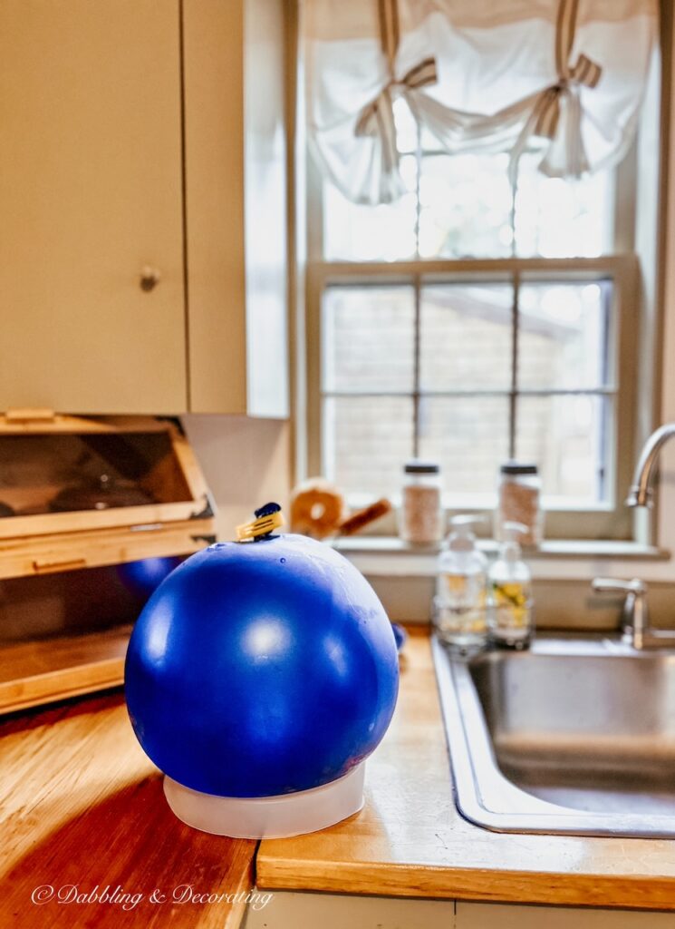 Ice lantern blue balloon on kitchen counter filled with water.