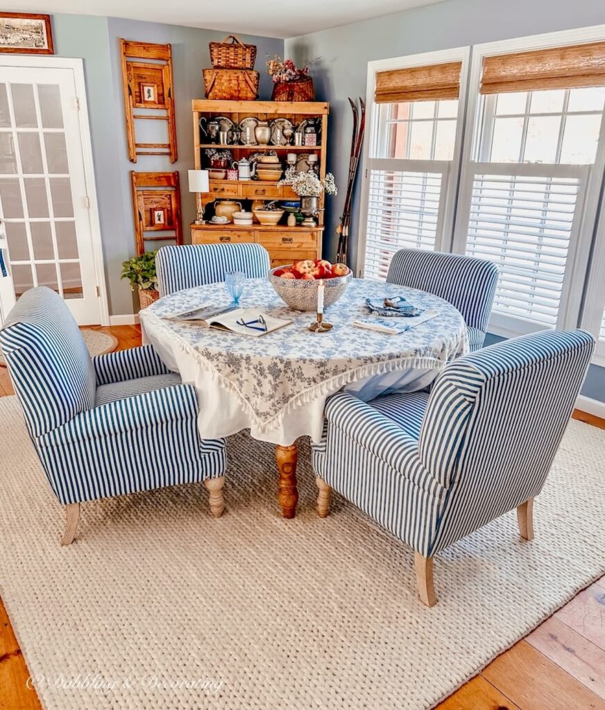 Blue and white dining room styled with vintage decor and three windows with bamboo shades.