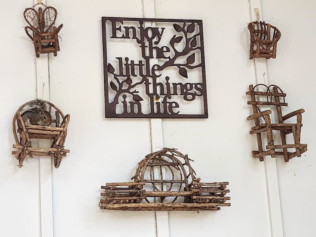 Vintage stick miniature chairs and Enjoy the Little Things in Life sign on outdoor wall with squirrel.