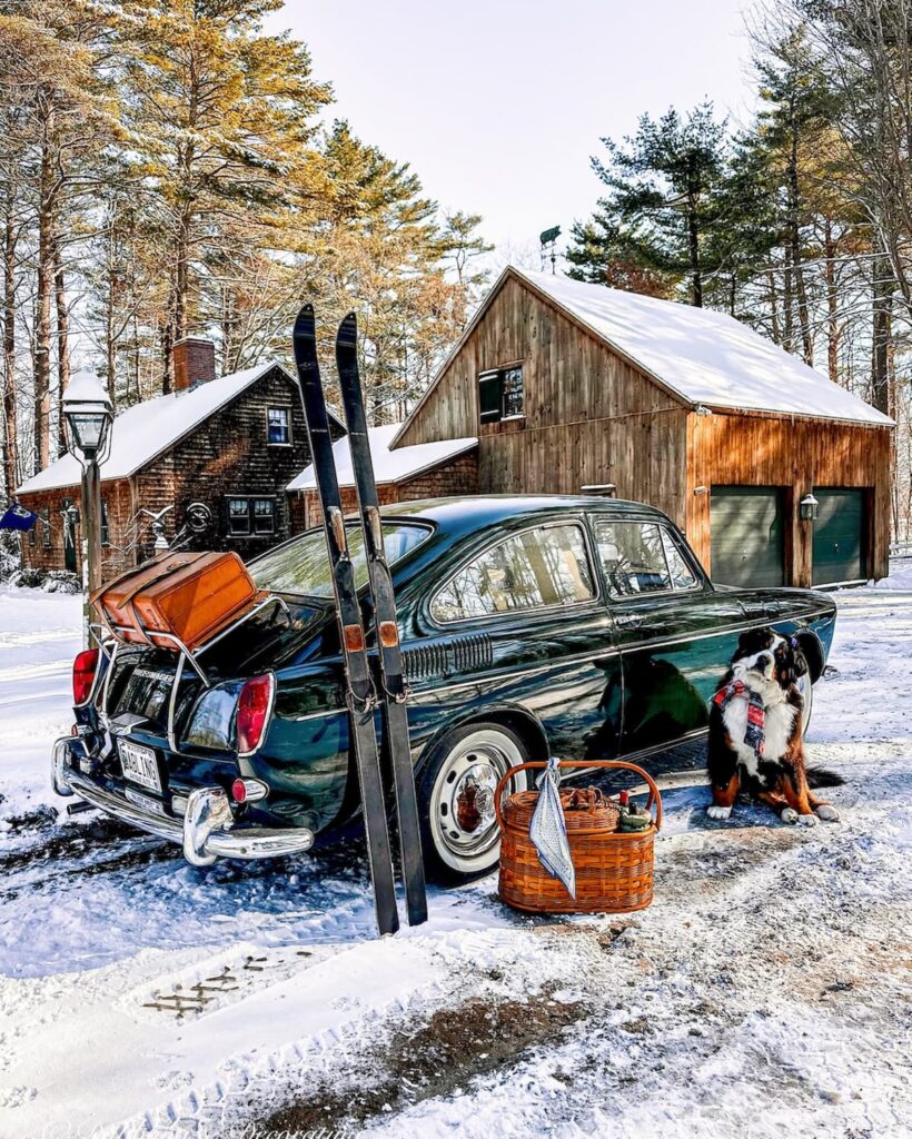 1968 VW Fastback in green with vintage HEAD skis, picnic basket and luggage on trunk with Bernese Mountain Dog in front of cedar shakes home on a snow day.  Alpine and Nordic decor series.