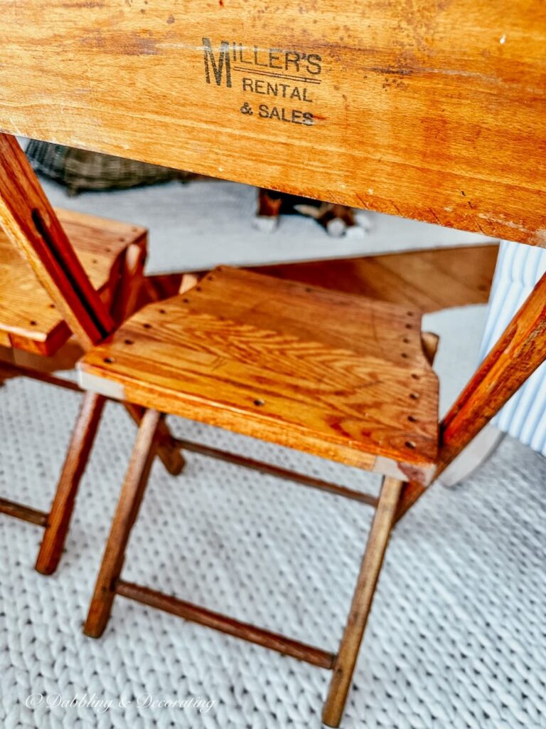 A close up shot of the words Miller's Rental & Sales on the back of a folding vintage oak chair.