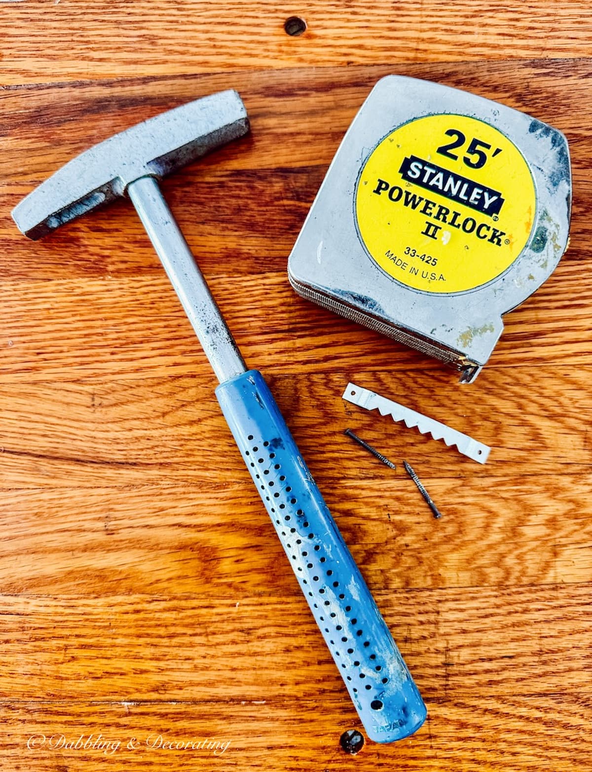 Hammer, measuring tape, and sawtooth hangers with screws.