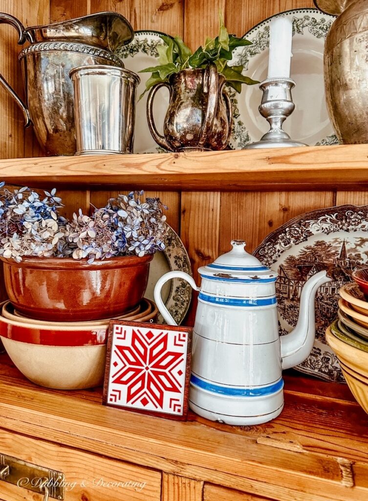 Red and white snowflake small art piece in vintage styled hutch.