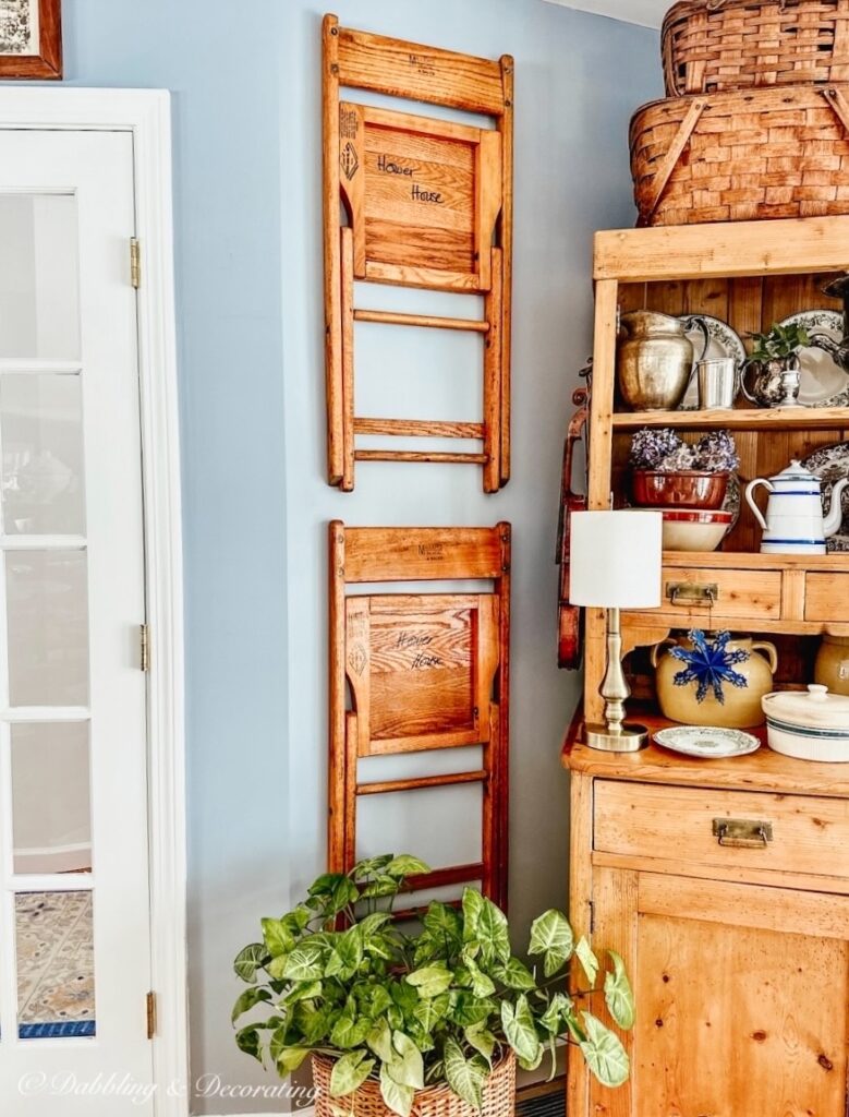 Vintage wall decor chairs hanging next to vintage pine hutch in cozy nook.