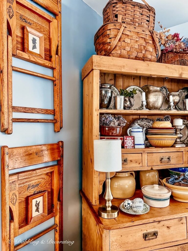 Vintage wall decor next to hutch with wooden chairs and thrifted silhouette pictures in dining room.