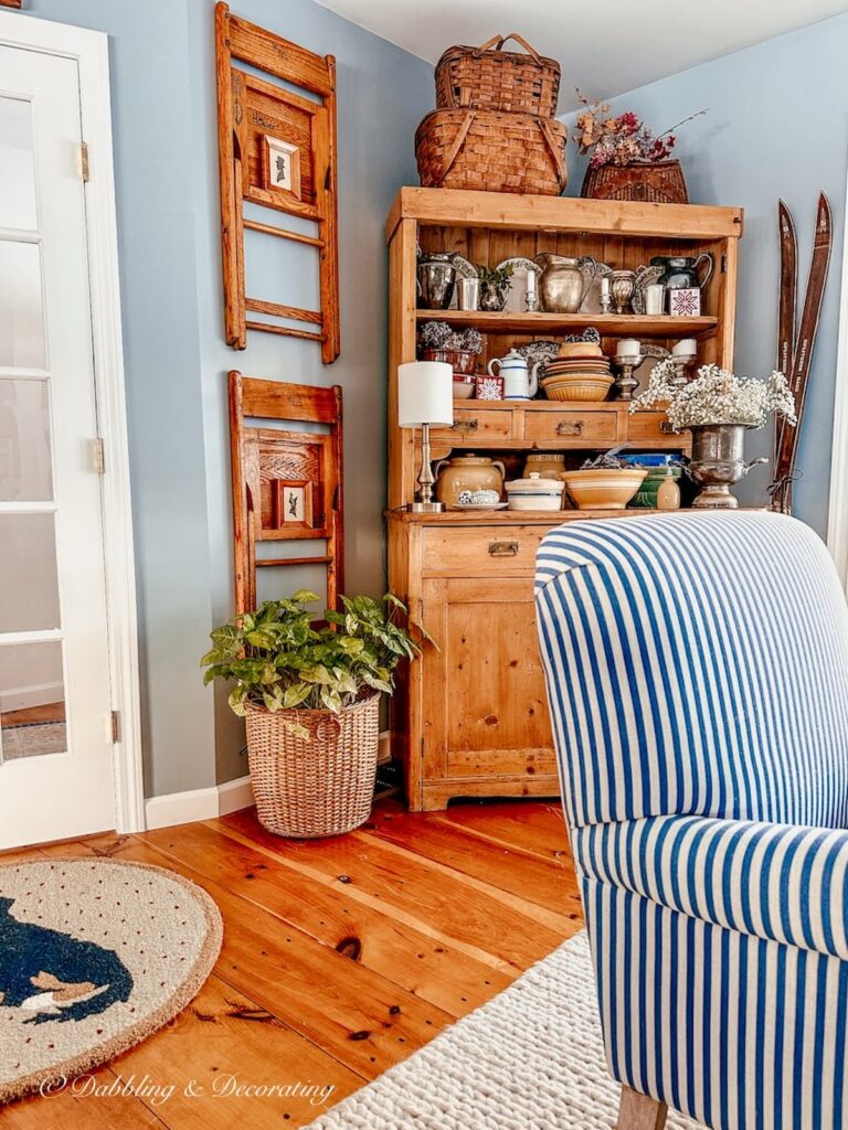 Vintage hutch with hanging vintage wall decor with chair collection on wall in dining room.