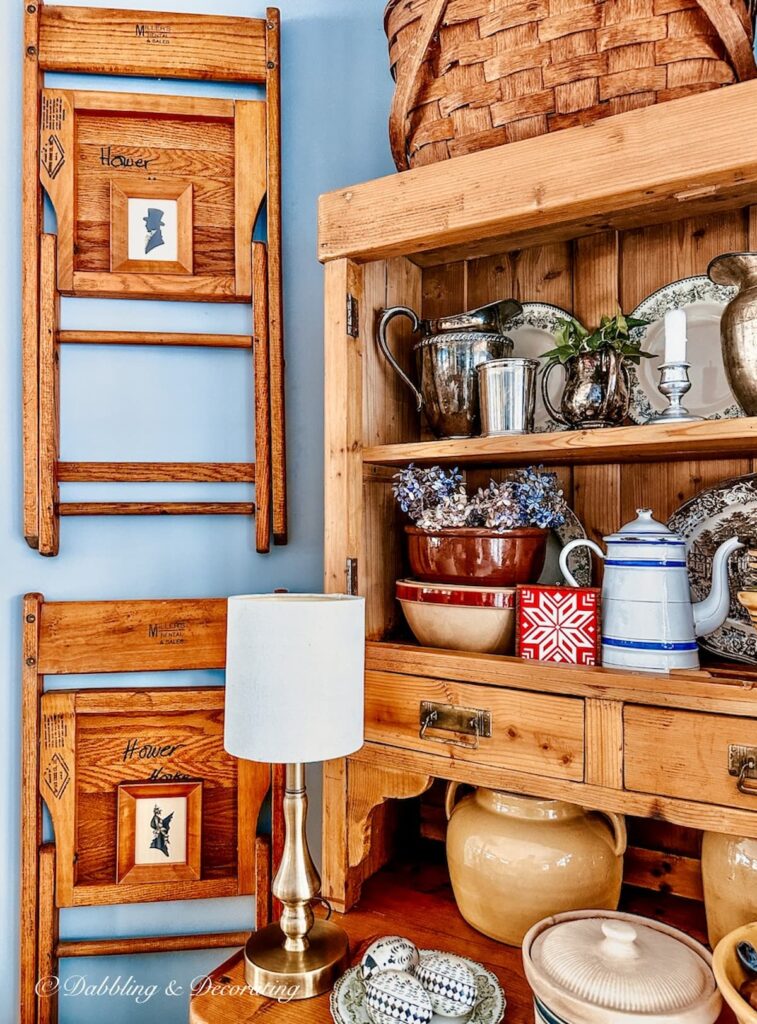 Vintage wall decor next to hutch with wooden chairs and thrifted silhouette pictures in dining room.