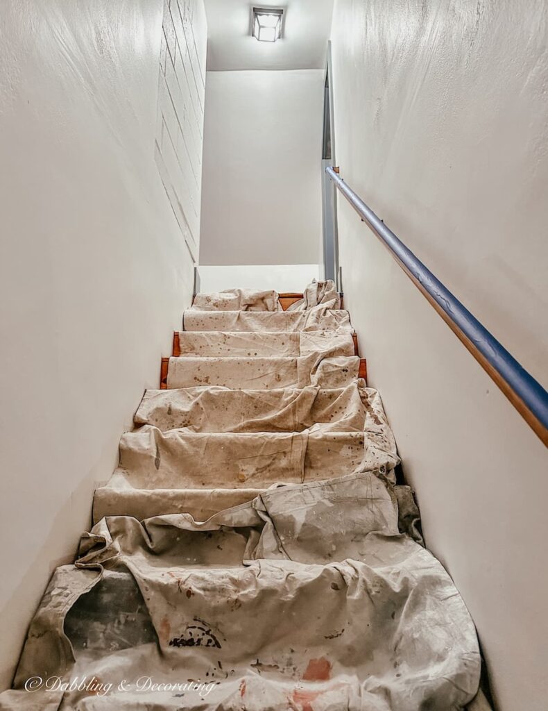 Stairs leading up to attic in home with painters tarps.