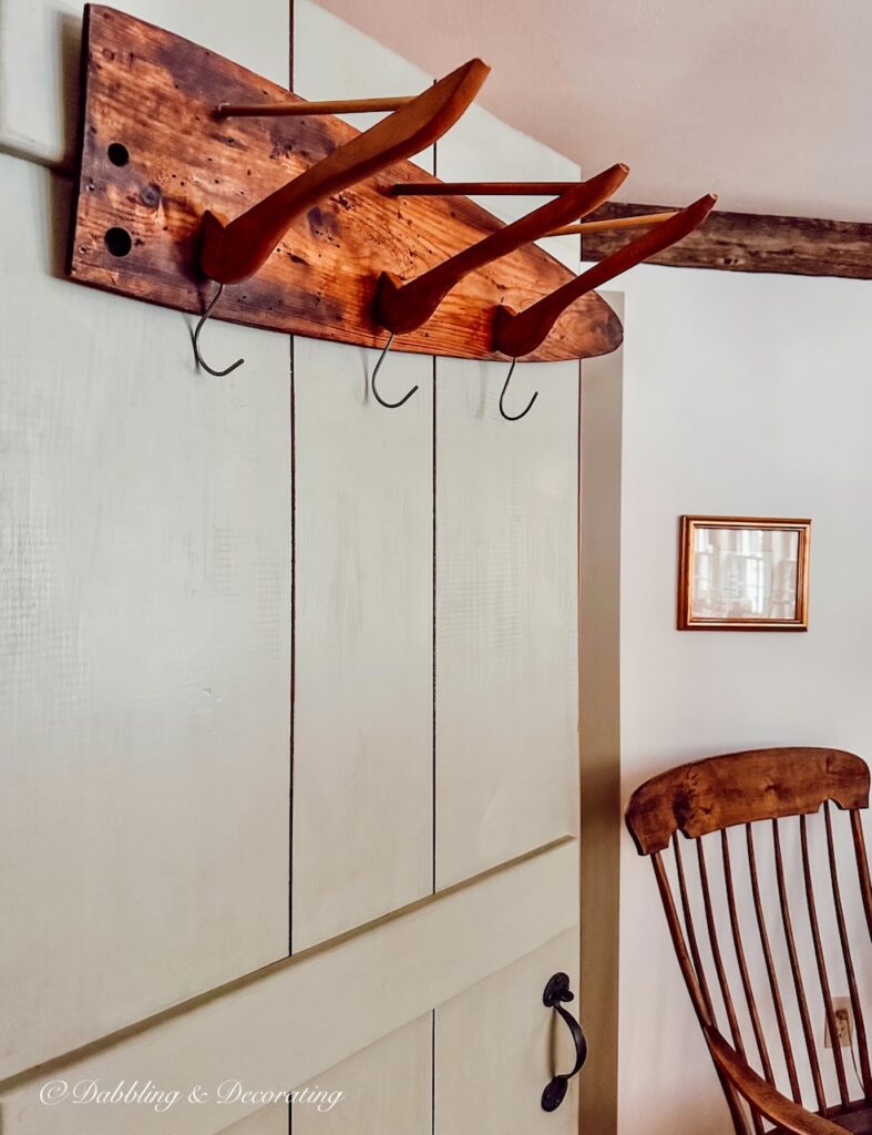 Antique wooden DIY coat rack hanging on an open antique pantry style door.