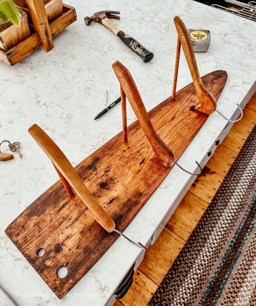 Antique trapper fur stretching board with three wooden clothes hangers cut to make a DIY Coat Rack.